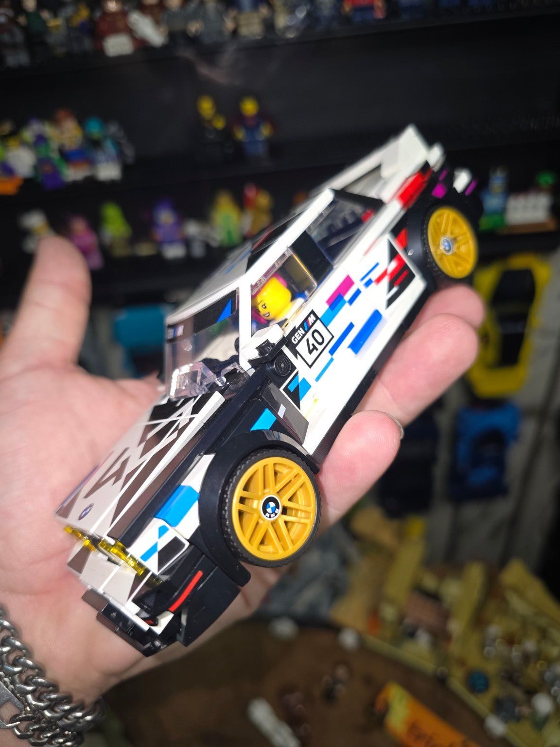 Built LEGO Speed Champions BMW M3 E30 held in hand, side view showing gold wheels and motorsport livery